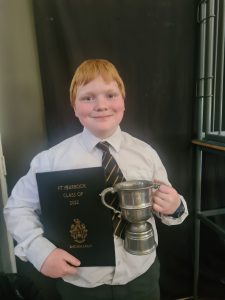 Young student holding a trophy and a certificate cheerful at Inchmarlo.