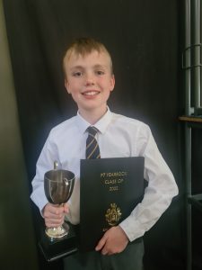 Young student holding a trophy and certificate at Inchmarlo School.