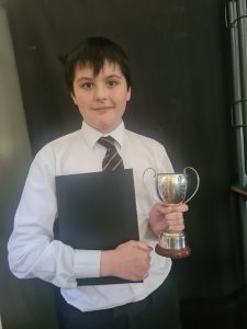 Young student holding trophy and certificate, celebrating academic success at Inchmarlo.
