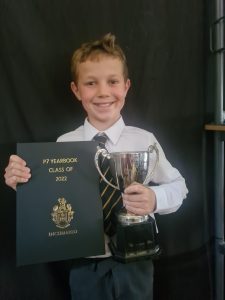 Young student holding trophy and certificate for achievement in 2022 class of 2022.