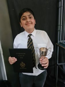 Child holding diploma and glass of water at Inchmarlo School graduation.