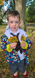 Child holding autumn leaves in park at Inchmarlo estate.