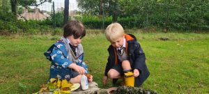 Two children playing and digging in a lush green garden.