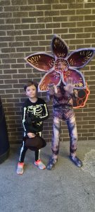 Two children standing next to a colorful butterfly cutout at Inchmarlo Gardens.