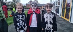 Three children dressed in skeleton costumes and vampire outfit at Inchmarlo outdoor event.