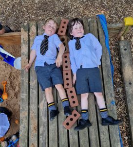 Two children lying on wooden playground equipment at Inchmarlo School playground.