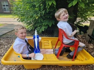 Children enjoying outdoor play at Inchmarlo with a yellow boat and outdoor seating.