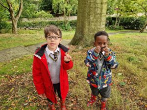 Two children enjoying outdoor activities at Inchmarlo preschool in a lush green park.
