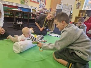 Child playing with baby doll in classroom environment.