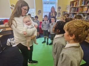 Young girl holding baby during storytime at Inchmarlo nursery.
