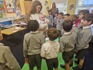 Bright classroom with young students and teacher engaging in learning activities.
