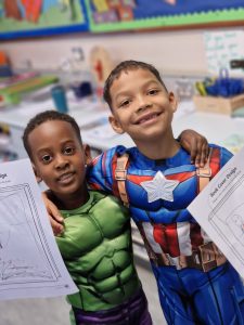Two happy children holding artwork at Inchmarlo School, highlighting high-quality education and student engagement.