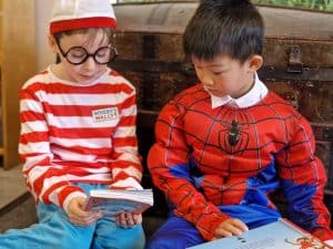 Two children in costumes reading books at Inchmarlo, highlighting a family-friendly atmosphere.