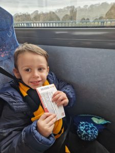 Smiling child on a bus, enjoying a trip to Inchmarlo residence in Scotland. Perfect for family travel and scenic journeys.