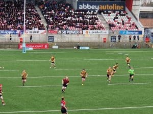 Rugby match at Inchmarlo with players and stadium seating in the background.