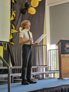 Young student giving a speech on stage at Inchmarlo School event.