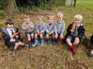 Young children sitting on the grass at Inchmarlo, Scotland, during outdoor playtime.