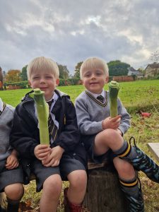 Two children holding spring onions outdoors at Inchmarlo.