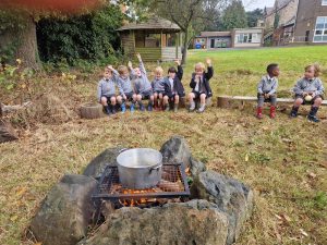 Children sitting by a campfire outdoors at Inchmarlo School.