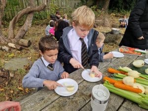 Children enjoying outdoor cooking activity at Inchmarlo with lush greenery in background.