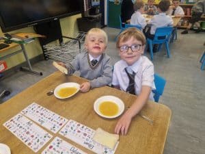 Two young children enjoying a meal at a classroom table, showcasing Inchmarlo’s nurturing educational environment.