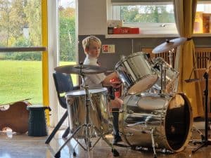 Child playing drums at Inchmarlo care home, engaging in musical activities.