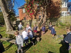 Children playing outdoors in a garden at Inchmarlo preschool.