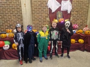 Children dressed in costumes for Halloween at Inchmarlo, surrounded by festive pumpkin decorations.