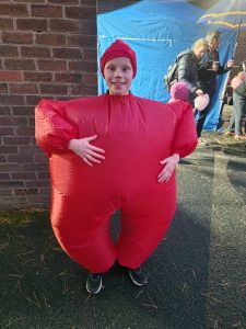 Child dressed in a red inflatable costume at Inchmarlo outdoor event, enjoying family fun and festivities.
