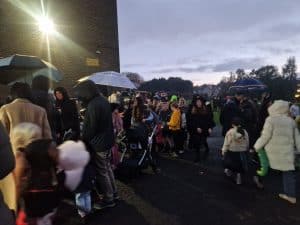 Crowd of people with umbrellas at Inchmarlo outdoor market in Scotland on a rainy day.