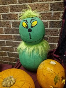 Colorful handcrafted pumpkin with a Dr. Seuss-inspired face and vibrant green fur, perfect for fall decor.