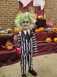 Young child in a Halloween costume with face paint and colorful wig at Inchmarlo estate.