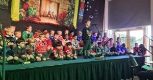 Students singing at Inchmarlo school assembly on stage.
