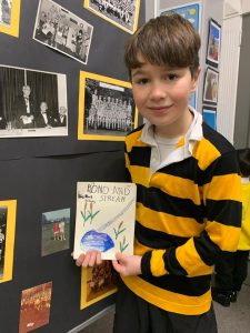 Young boy holding a colorful art project at Inchmarlo School.