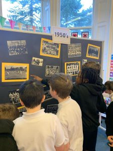 Children viewing vintage photos and information display about Inchmarlo estate from the 1950s.