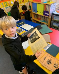 Young student reading a historical book in a colorful classroom.