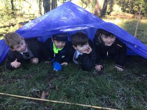 Children playing under a blue tent in scenic outdoor setting.