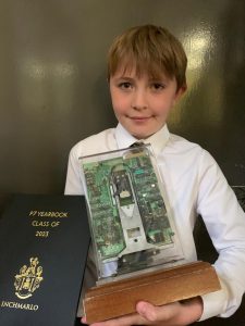 Young boy holding an award trophy and certificate at Inchmarlo.