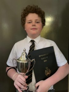 Young student holding trophy and certificate at Inchmarlo school event.