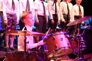 Young boy playing drums at Inchmarlo music event, lively performance, kids entertainment.