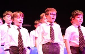 Young boys singing on stage during a school performance.