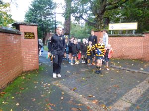 Children and staff gather near Inchmarlo school entrance on a rainy day.