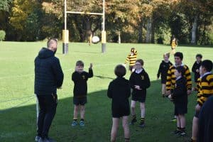 Young students practicing rugby on lush green field at Inchmarlo School.