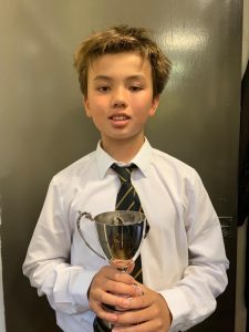 Young boy in school uniform holding a trophy, celebrating achievement at Inchmarlo.