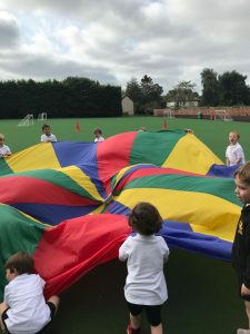 Children playing with a colorful parachute outdoor at Inchmarlo.