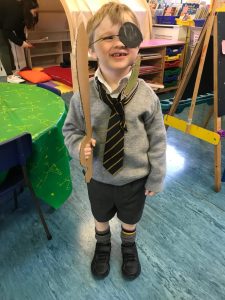 Young boy in school uniform with an eye patch, smiling at Inchmarlo preschool.