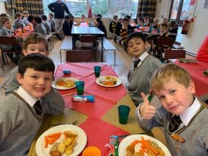 Smiling children enjoying meal at Inchmarlo school cafeteria. Happy students dining together in bright, cheerful environment.