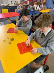 Children working on a creative craft project in a classroom setting.