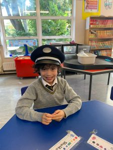 Young student smiling at school desk in classroom, learning and playing.