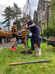 Children and staff planting a young tree outside Inchmarlo estate.